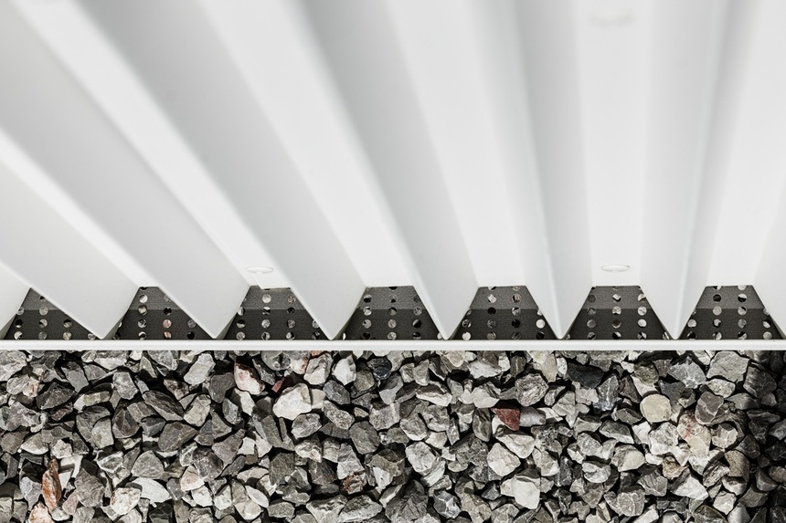 Detail profilování bílého hliníkového plechu Prefalz s pravidelným lichoběžníkovým vzorem fasády.